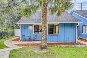 a blue house with a palm tree in front of it at Charming home near beach & golf with central AC & patio - dog-friendly in Palm Coast