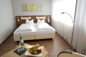 ein Schlafzimmer mit einem Bett und einem Tisch mit einer Schale Obst in der Unterkunft Landhotel Mutter Althoff in Olfen
