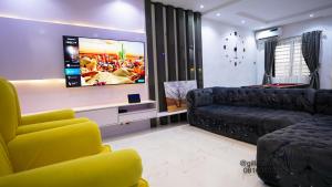 Gillant Luxury Homes في بنين سيتي: غرفة معيشة مع أريكة وتلفزيون بشاشة مسطحة