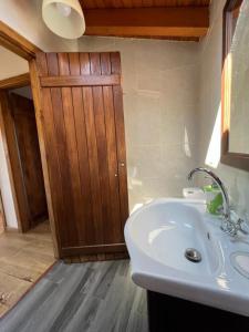 Un baño con lavabo y puerta de madera. en Casal de Pedra, en Santa Irene
