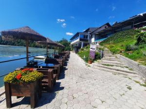 a row of tables and umbrellas next to a river at Gostisce Jezero in Medvode