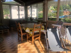 uma mesa e cadeiras num quarto com janelas em Chalet Heidi em Serrada