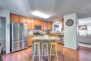 a kitchen with wooden cabinets and a island with bar stools at Elkridge Townhome about 15 Mi to Dtwn Baltimore! in Elkridge