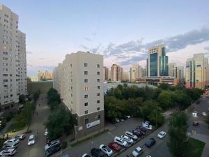 a city with cars parked in a parking lot at Апартаменты в центре города in Astana