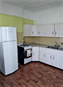 eine Küche mit weißen Schränken und einem weißen Kühlschrank in der Unterkunft Inmuebles V&S in Río Gallegos
