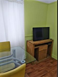 ein Wohnzimmer mit einem TV und einem Glastisch in der Unterkunft Inmuebles V&S in Río Gallegos
