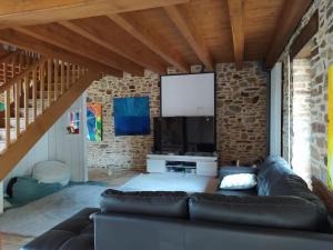 a living room with a couch and a flat screen tv at Gîte de charme en Dordogne avec Piscine et jardin in Jumilhac-le-Grand