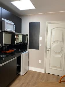a kitchen with a white door and a microwave at prudente 304 in Rio de Janeiro