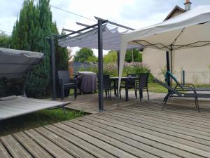 a deck with a table and chairs under a white umbrella at Gîte de charme en Dordogne avec Piscine et jardin in Jumilhac-le-Grand