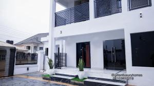 a white house with benches in front of it at Gillant Luxury Homes in Benin City