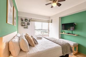 - une chambre avec des murs verts et un lit avec des oreillers dans l'établissement ALU Apartments - Limit with Miraflores Panoramic City View, à Lima