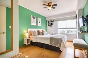 1 dormitorio con paredes verdes y 1 cama con ventilador de techo en ALU Apartments - Limit with Miraflores Panoramic City View, en Lima