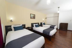 um quarto de hotel com duas camas com almofadas azuis em Hotel Boutique Selva Alegre em Arequipa