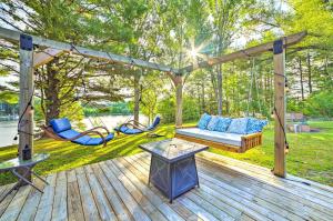 a wooden deck with a swing and a bench at Riverfront Home with Dock about 6 Mi to Cheboygan! in Cheboygan