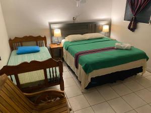 a bedroom with two beds with green sheets and a chair at Nanda Parbat Hostal in San Rafael Cedros