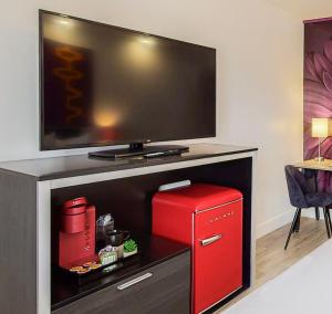 a room with a red refrigerator and a tv at Hotel ZAZZ in Albuquerque