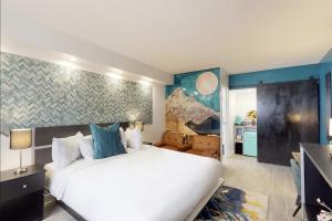 Hotel ZAZZ في ألباكيركي: غرفة نوم بسرير ابيض كبير وجدران زرقاء