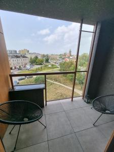 キェルツェにあるApartament Ventus Business and Living 46のバルコニー(椅子2脚、大きな窓付)