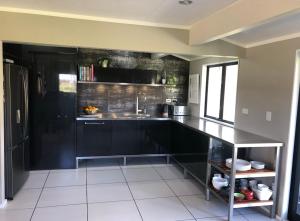 a kitchen with black cabinets and a sink in it at Rural Stay On City Doorstep in Palmerston North