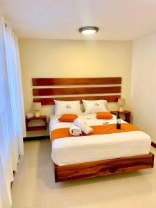 sypialnia z dużym łóżkiem z białą pościelą i pomarańczowymi poduszkami w obiekcie La Posada de Mindo w mieście Mindo