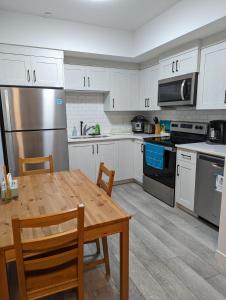 een keuken met witte kasten en een houten tafel bij Livingston Howse Haven - A simple & cozy private two-bedroom basement suite with free parking in Calgary