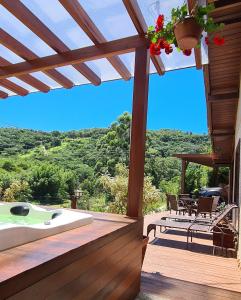 een patio met een bad en een tafel en stoelen bij Valle Paradiso in Praia do Rosa