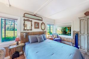 1 dormitorio con 1 cama azul y ventanas en Vineyard Cottage, en Guerneville