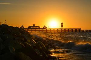 a pier in the ocean with the sun in the background at Iracema Praia Flats in Fortaleza