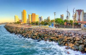a stone wall next to the water with buildings at Iracema Praia Flats in Fortaleza
