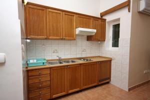 a kitchen with wooden cabinets and a sink at Apartments by the sea Rogoznica - 3094 in Rogoznica