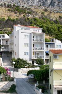 a large white apartment building in front of a mountain at Apartments with a parking space Duce, Omis - 3190 in Duće