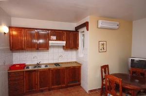 uma cozinha com armários de madeira, uma mesa e um lavatório em Apartments by the sea Rogoznica - 3197 em Rogoznica