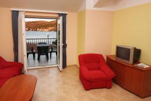 a living room with two red chairs and a television at Apartments by the sea Rogoznica - 3200 in Rogoznica