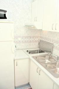 a white kitchen with a sink and a refrigerator at Double Room Zivogosce - Porat 2733a in Živogošće