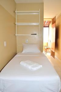 um quarto com uma cama com lençóis brancos e prateleiras em Iracema Praia Flats em Fortaleza