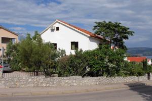 a white house with a stone fence and trees at Apartments and rooms with parking space Krk - 3231 in Vrh