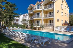 a hotel with a swimming pool and chairs in front of a building at Apartments with swimming pool Jadranovo, Crikvenica - 3238 in Jadranovo