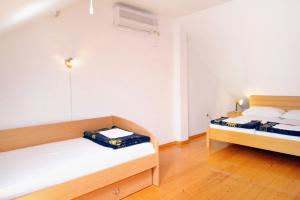 two beds in a room with white walls and wooden floors at Apartments with swimming pool Jadranovo, Crikvenica - 3238 in Jadranovo