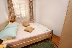 a bed with two pillows in a room with a window at Apartments by the sea Selce, Crikvenica - 3240 in Selce