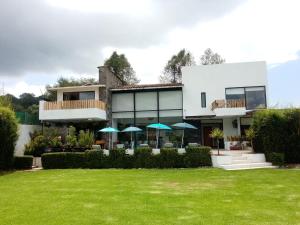 una casa con un patio verde con sombrillas en Casa Nicolás en Valle de Bravo