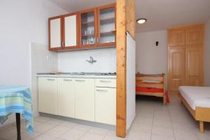 a kitchen with white cabinets and a bed in a room at Family friendly seaside apartments Jagodna, Hvar - 3250 in Jelsa