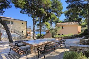 a patio with benches and a table and a building at Double Room Rogoznica 3266a in Rogoznica