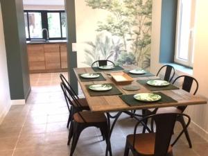 a dining room with a wooden table and chairs at Charmant Gîte Familial Rénové avec 3 Chambres, Cheminée et Jardin, Proche Le Mans - FR-1-410-332 in Le Mans