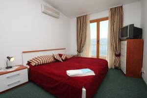a bedroom with a red bed and a television at Rooms by the sea Metajna, Pag - 3305 in Zubovići