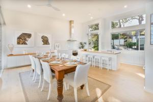 a kitchen and dining room with a wooden table and chairs at The Sands Mollymook Luxury Beach House in Mollymook