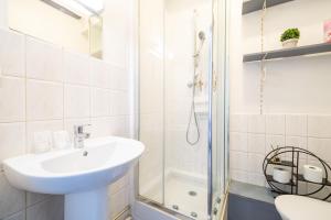La salle de bains blanche est pourvue d'un lavabo et d'une douche. dans l'établissement LoveLoc, à Lille