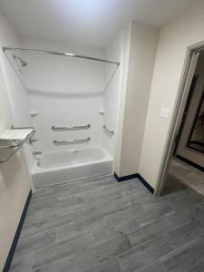 een witte badkamer met een bad en een tegelvloer bij Fairway Inn in Iowa
