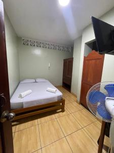 a bedroom with a bed and a tv and a chair at Alojamiento tahuari in Iquitos