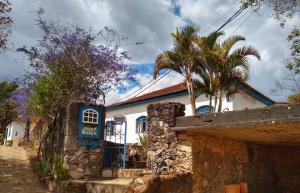 a white house with a blue door and palm trees at Pouso do Bizuca in Tiradentes