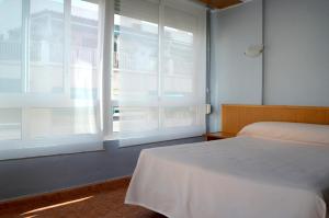 ein Schlafzimmer mit einem Bett und einem großen Fenster in der Unterkunft Hotel Cervantes in Alicante